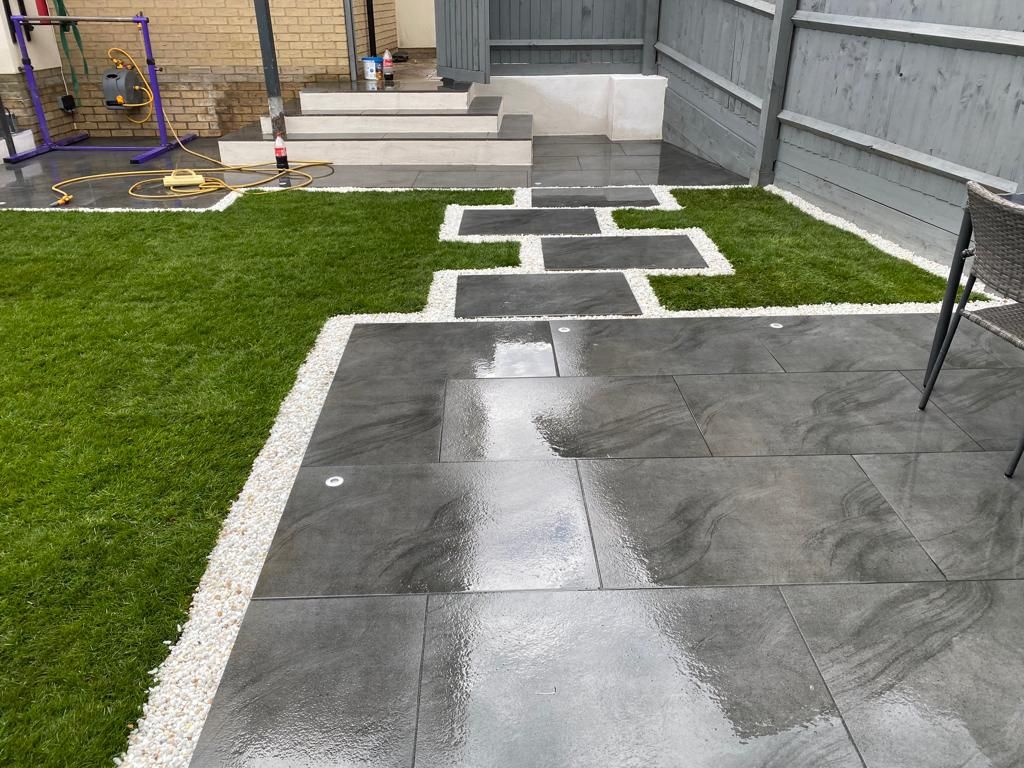 Modern garden with dark porcelain stepping stones, white gravel and artificial grass