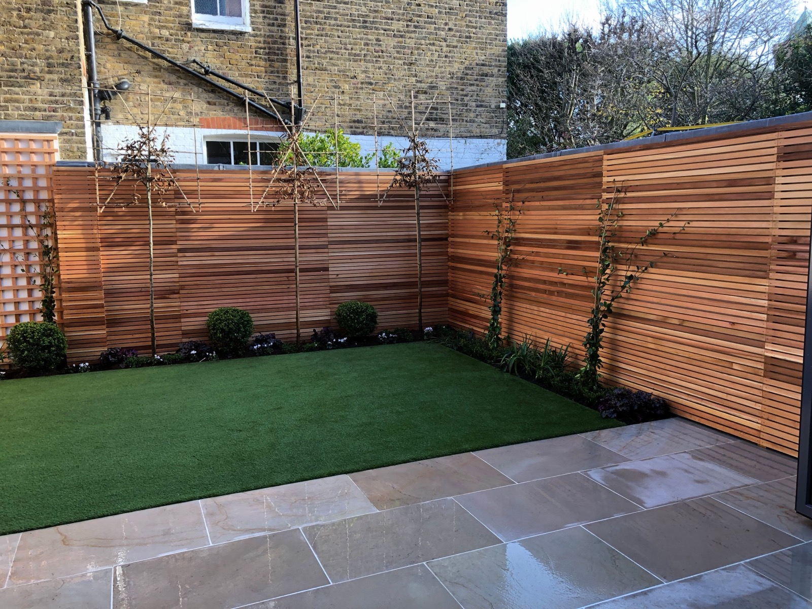 A beautifully landscaped garden with lawn, stepping stones and raised planters